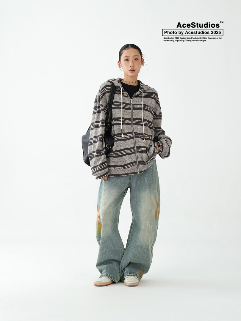 Model wearing a striped zip-up hoodie with baggy jeans and a black backpack