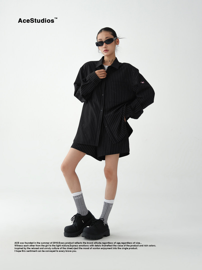 Model wearing a black pinstriped oversized shirt and shorts with sunglasses