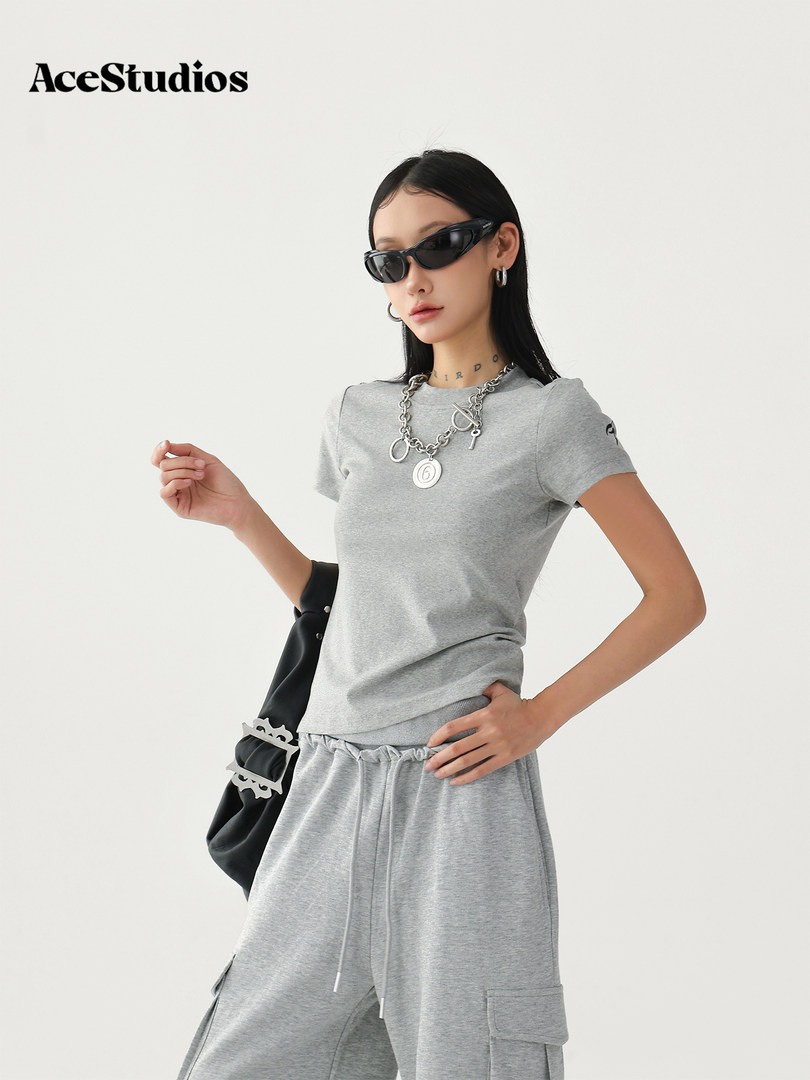 Model wearing a gray casual streetwear outfit with sunglasses and chain necklace