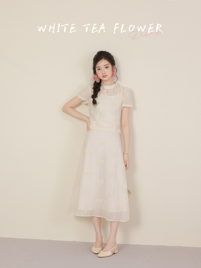 Model wearing a white sheer floral dress with matching flats