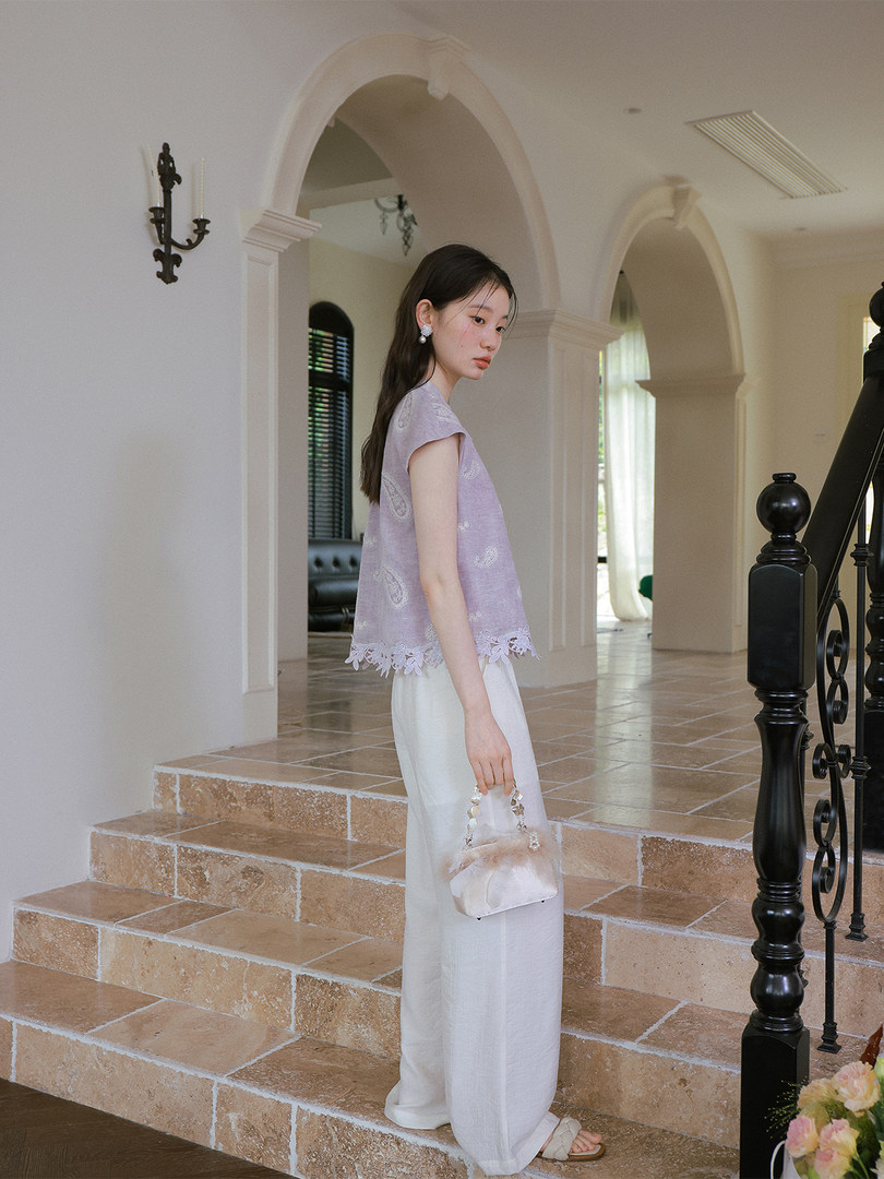 Model wearing a lilac sleeveless top with white wide-leg pants