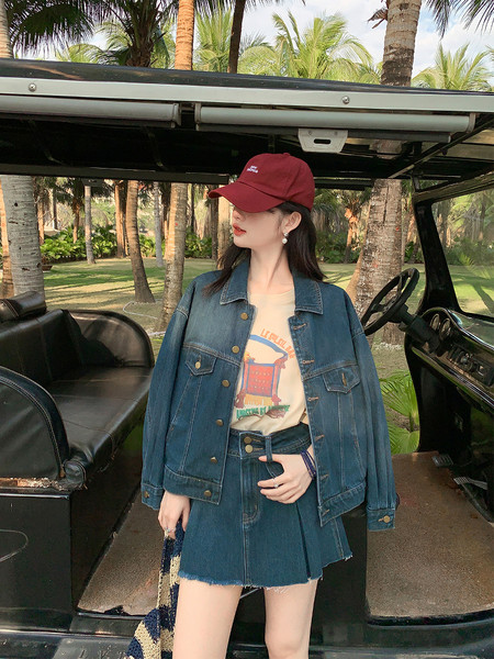 Woman wearing a denim jacket and matching denim skirt with a baseball cap