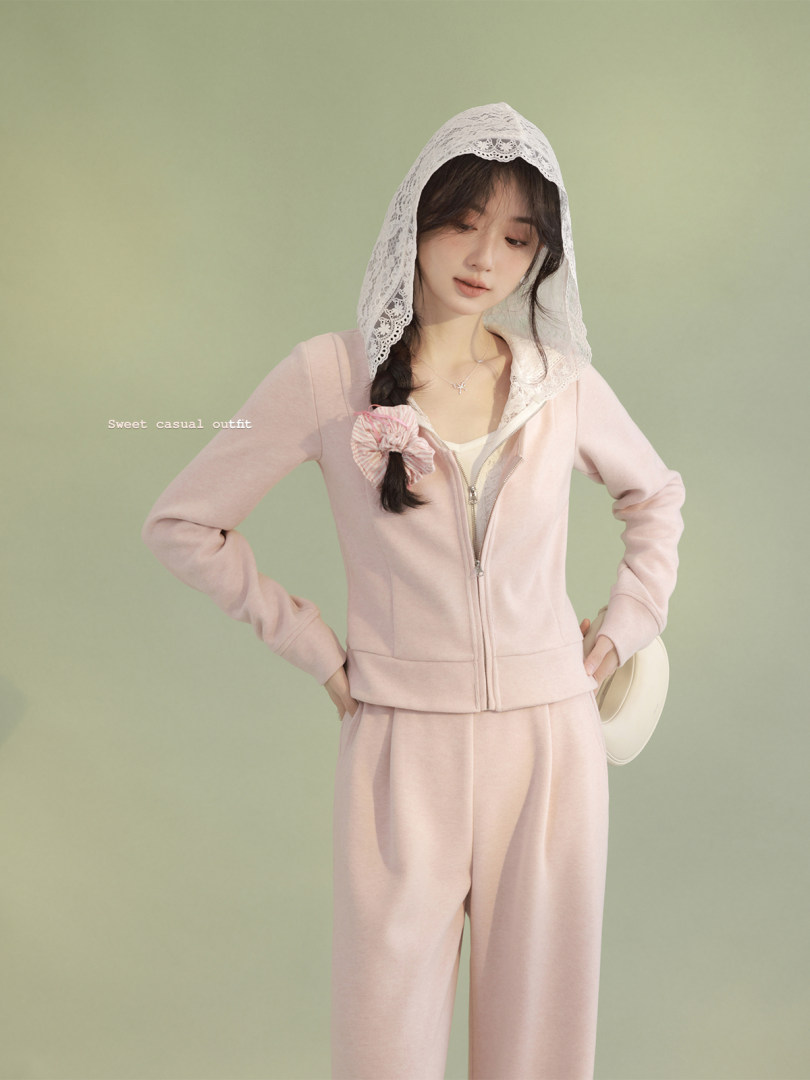 Model wearing a pastel pink hooded zip-up top and matching pants set