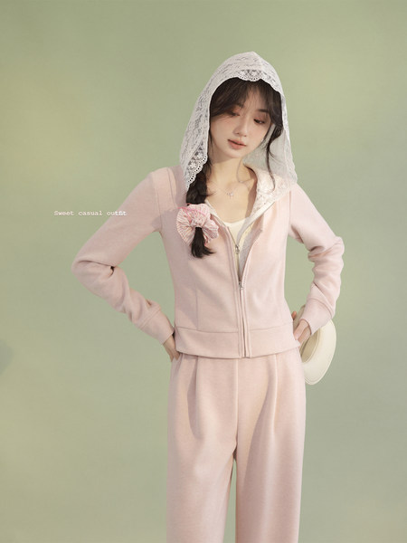Model wearing a pastel pink hooded zip-up top and matching pants set
