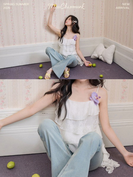 Model wearing a white ruffled camisole top with light blue jeans