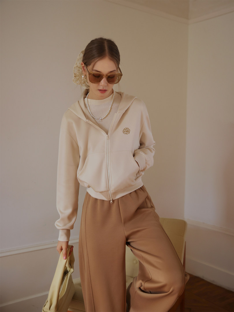 Model wearing a beige zip-up hoodie and brown wide-leg pants