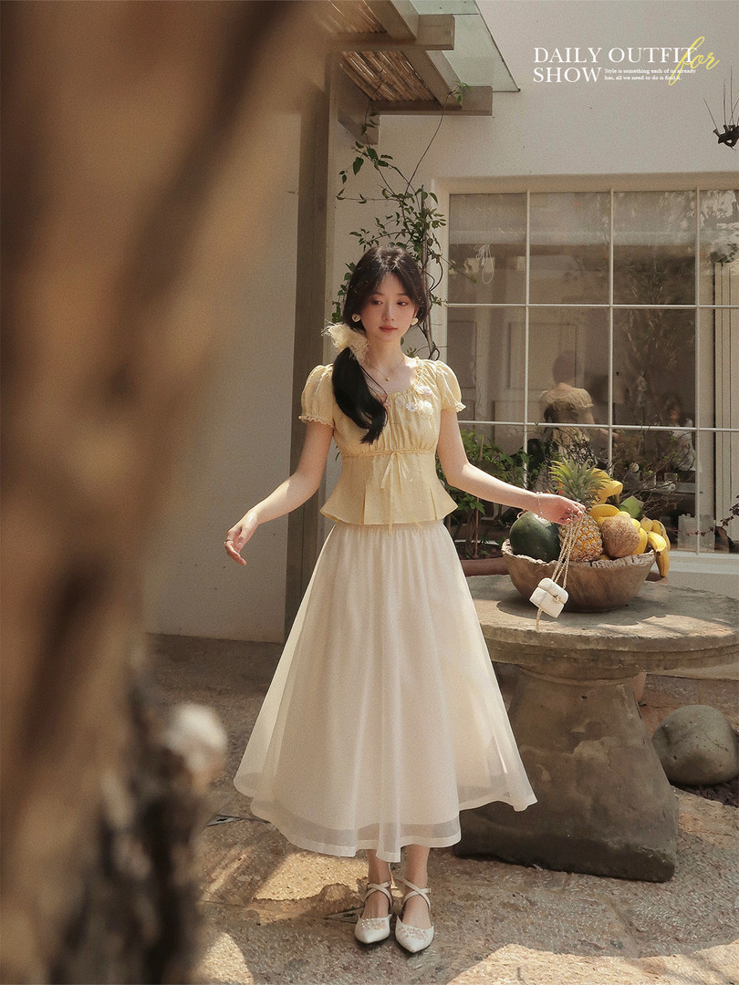 Young woman wearing a light yellow and white flowy dress outdoors