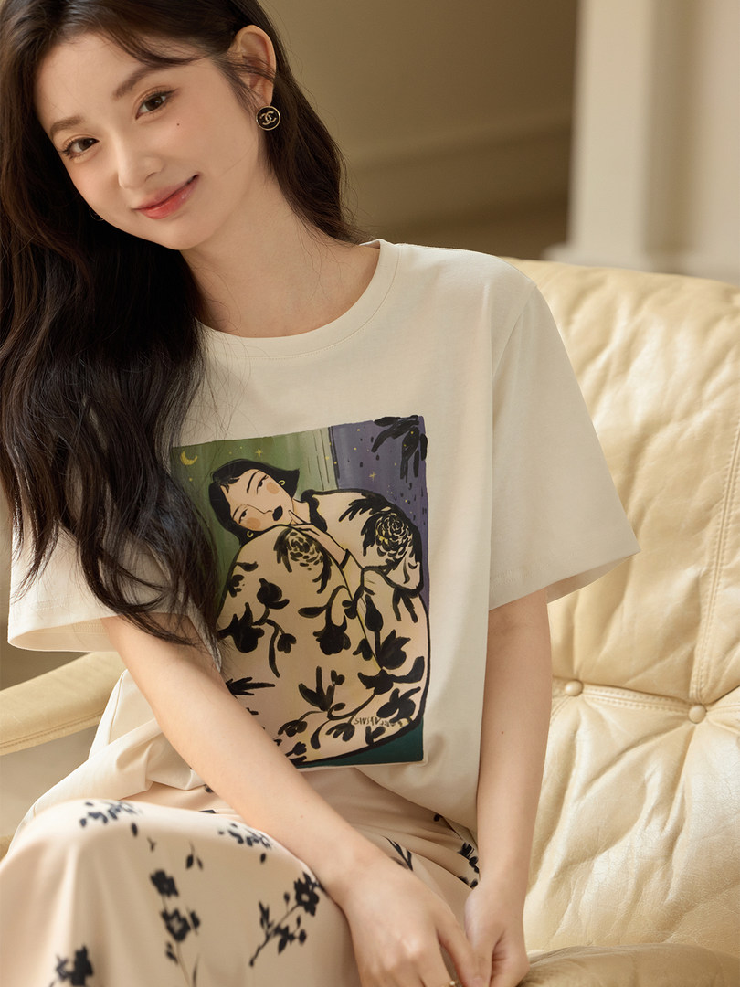 Woman modeling a cream graphic T-shirt and matching patterned loungewear pants