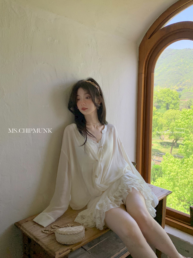 Woman wearing a white sheer lace-trimmed dress blouse indoors by a window