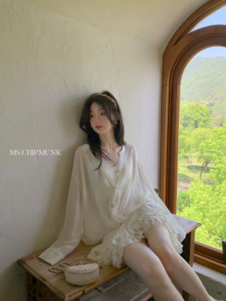 Woman wearing a white sheer lace-trimmed dress blouse indoors by a window