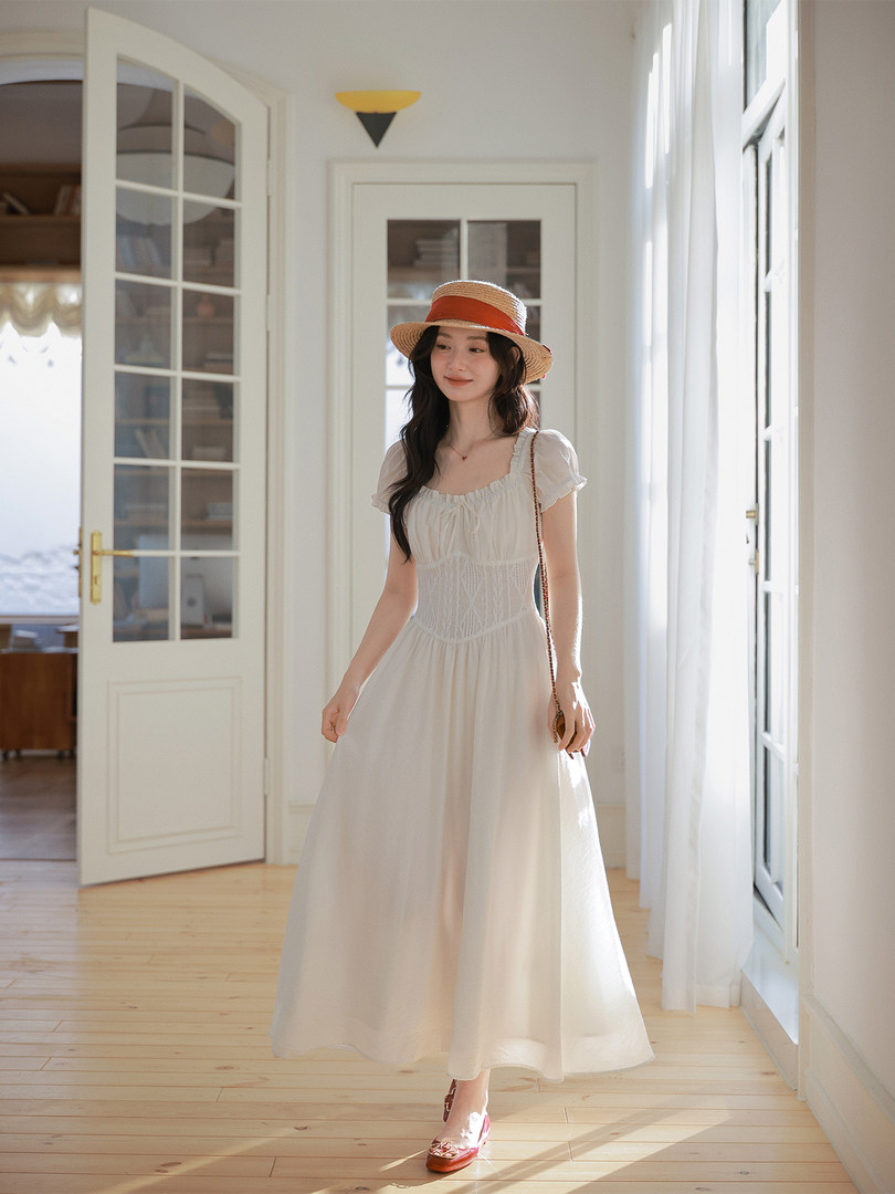 Woman wearing a white maxi dress and straw hat indoors