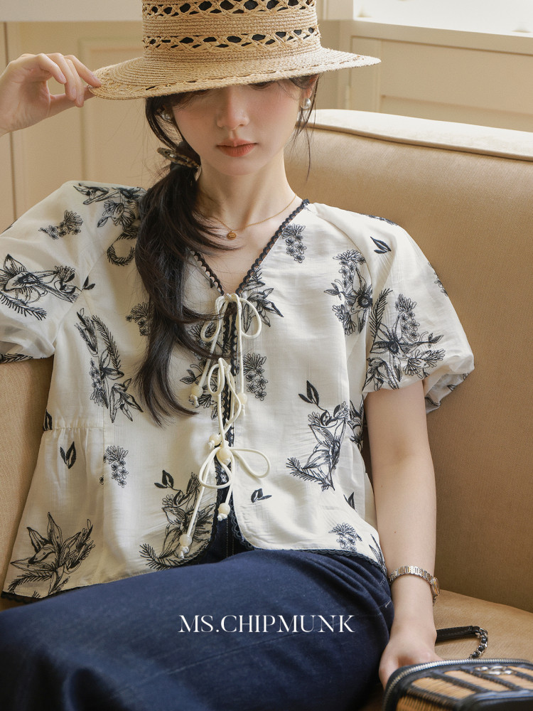 Woman wearing a floral short-sleeve blouse with a straw hat