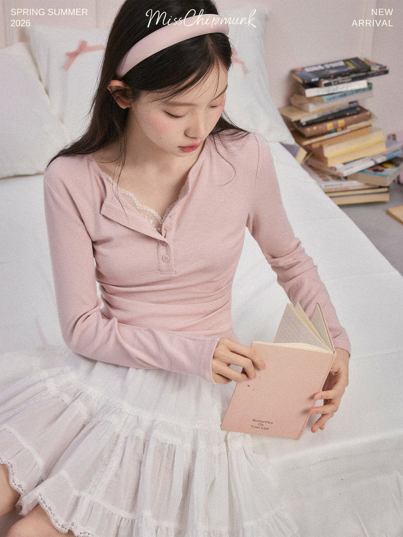 Woman wearing a pink long-sleeve top and white tulle skirt while sitting on a bed