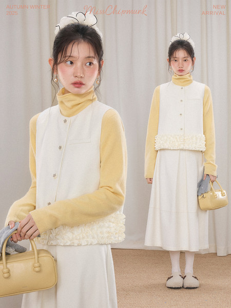 Model wearing a white sleeveless vest over a yellow turtleneck and cream long skirt