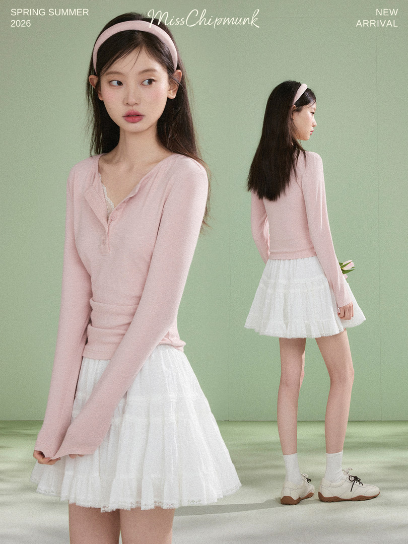 Model wearing a pink long-sleeve top and white pleated skirt