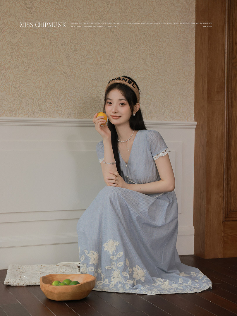 Woman wearing a light blue floral lace dress seated indoors