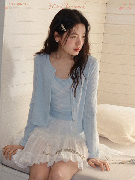 Model wearing a light blue cardigan and top with a sheer white skirt
