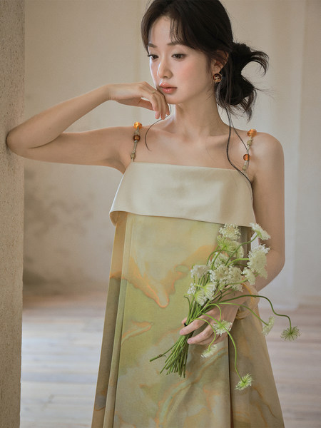 Sleeveless flowing pastel dress worn by a model holding flowers