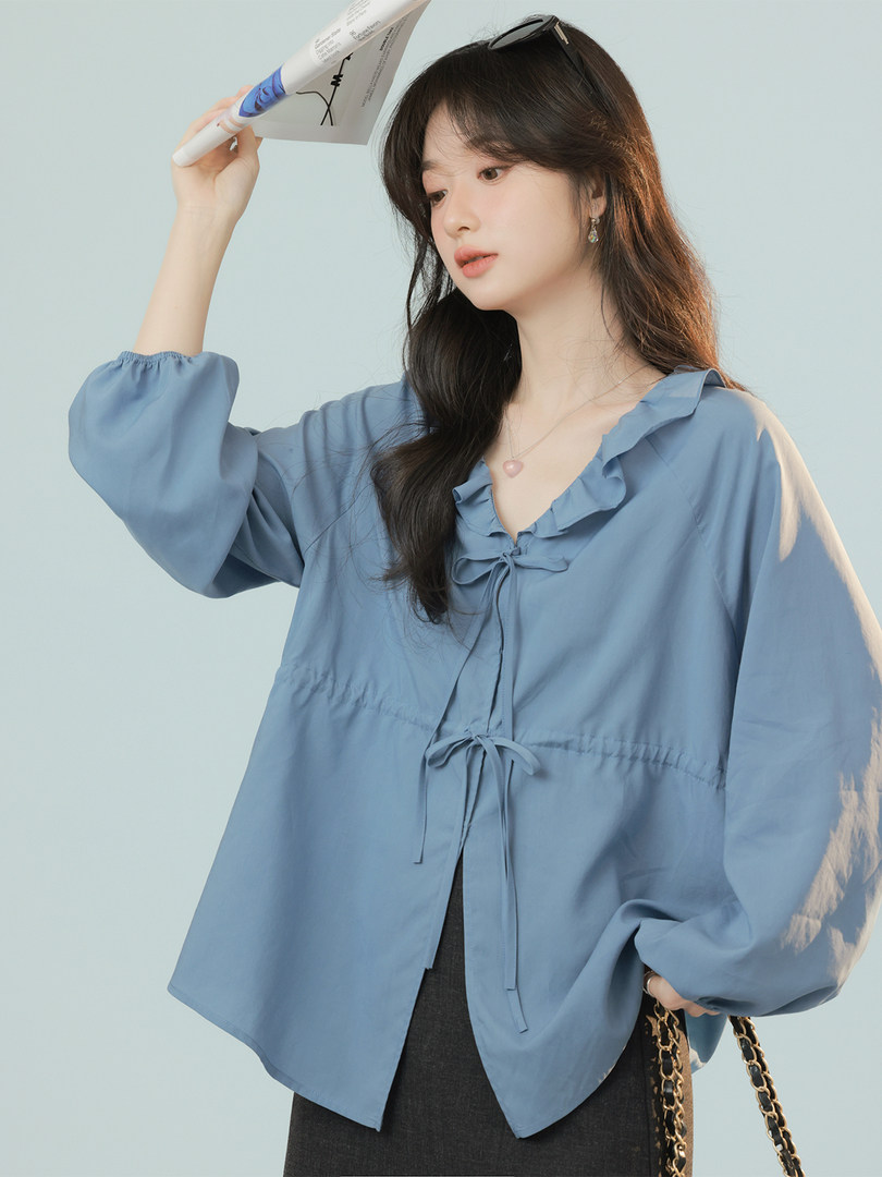 Model wearing a blue ruffled tie-front blouse