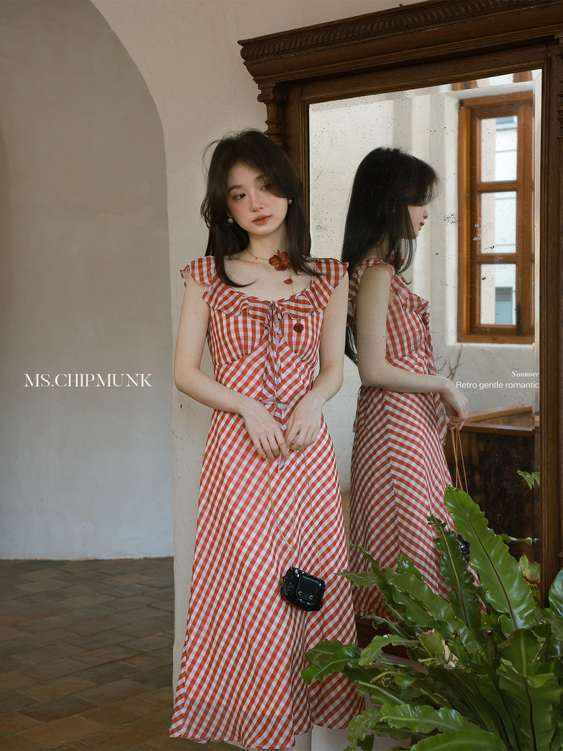 Model wearing an orange and white gingham ruffled dress indoors