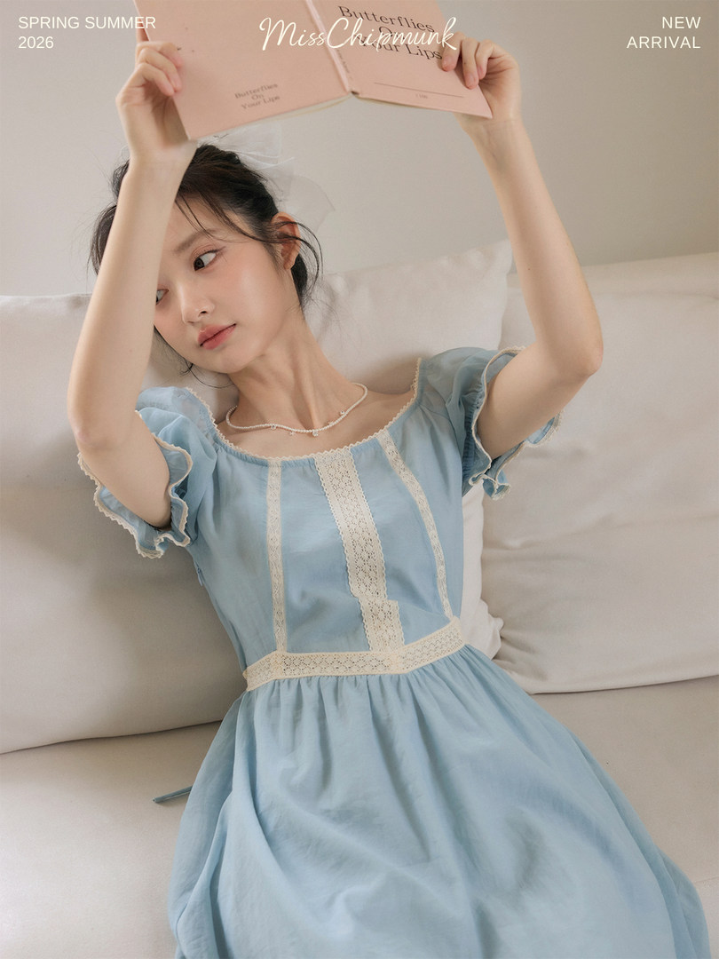 Model wearing a light blue puff-sleeve dress with lace trim