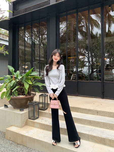 Model wearing a light gray top and cardigan with black wide-leg pants and a pink quilted handbag