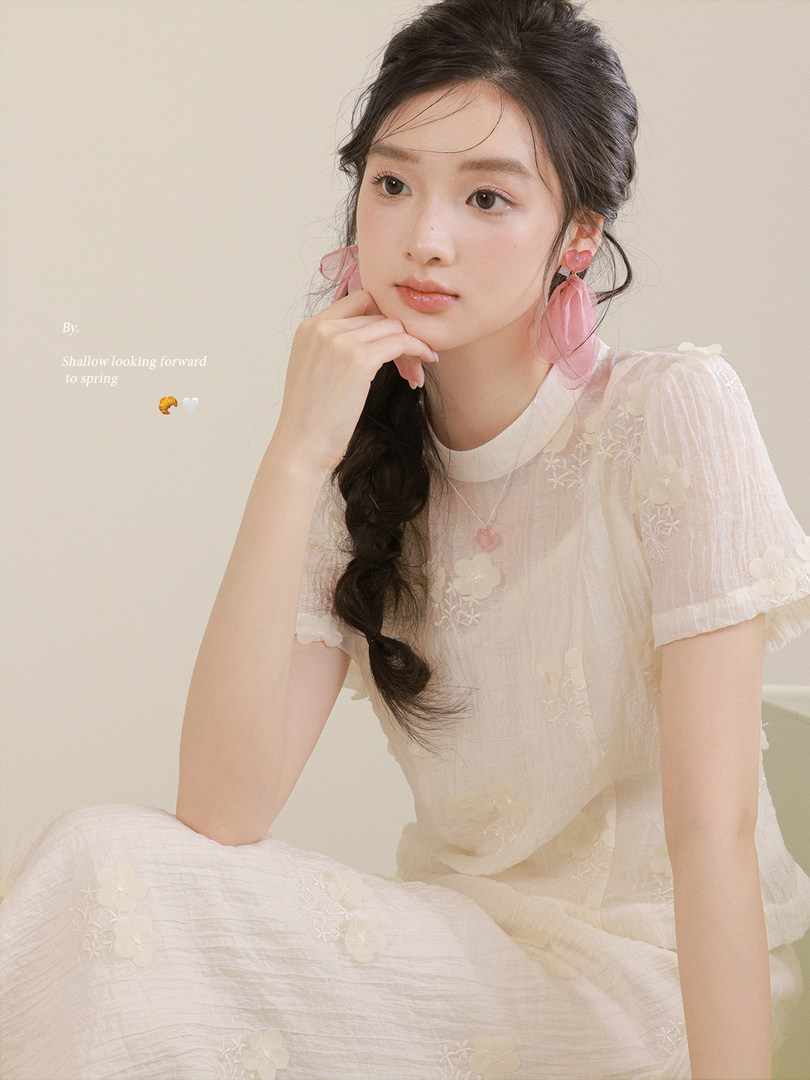 Model wearing a sheer floral white dress with pink earrings