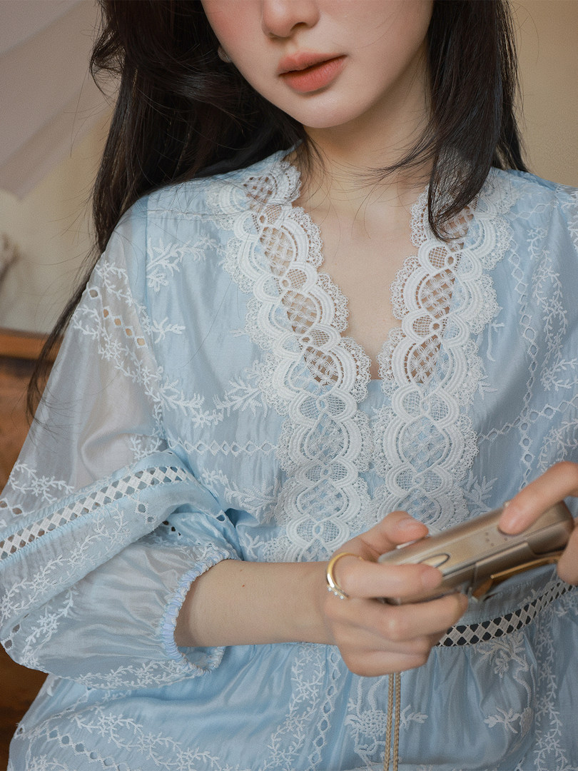 Woman wearing a light blue lace dress with sheer embroidered details