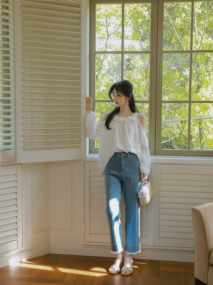 Woman wearing a white blouse with blue jeans and sandals indoors