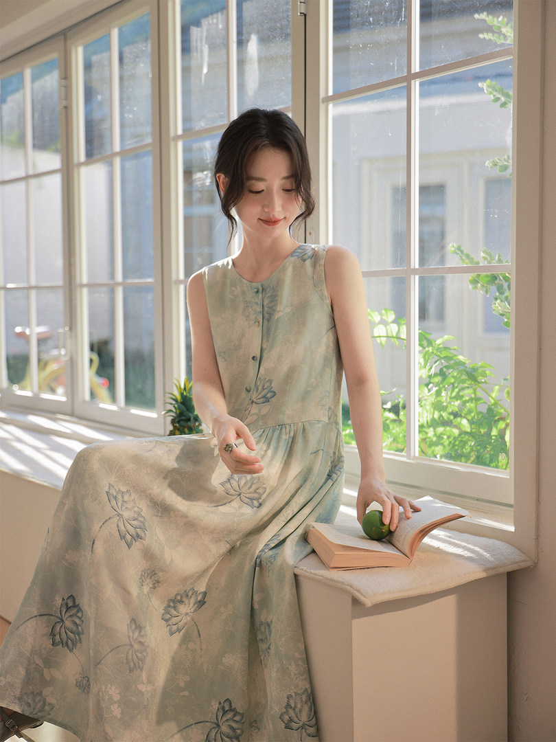 Sleeveless floral maxi dress worn by a woman indoors by a window