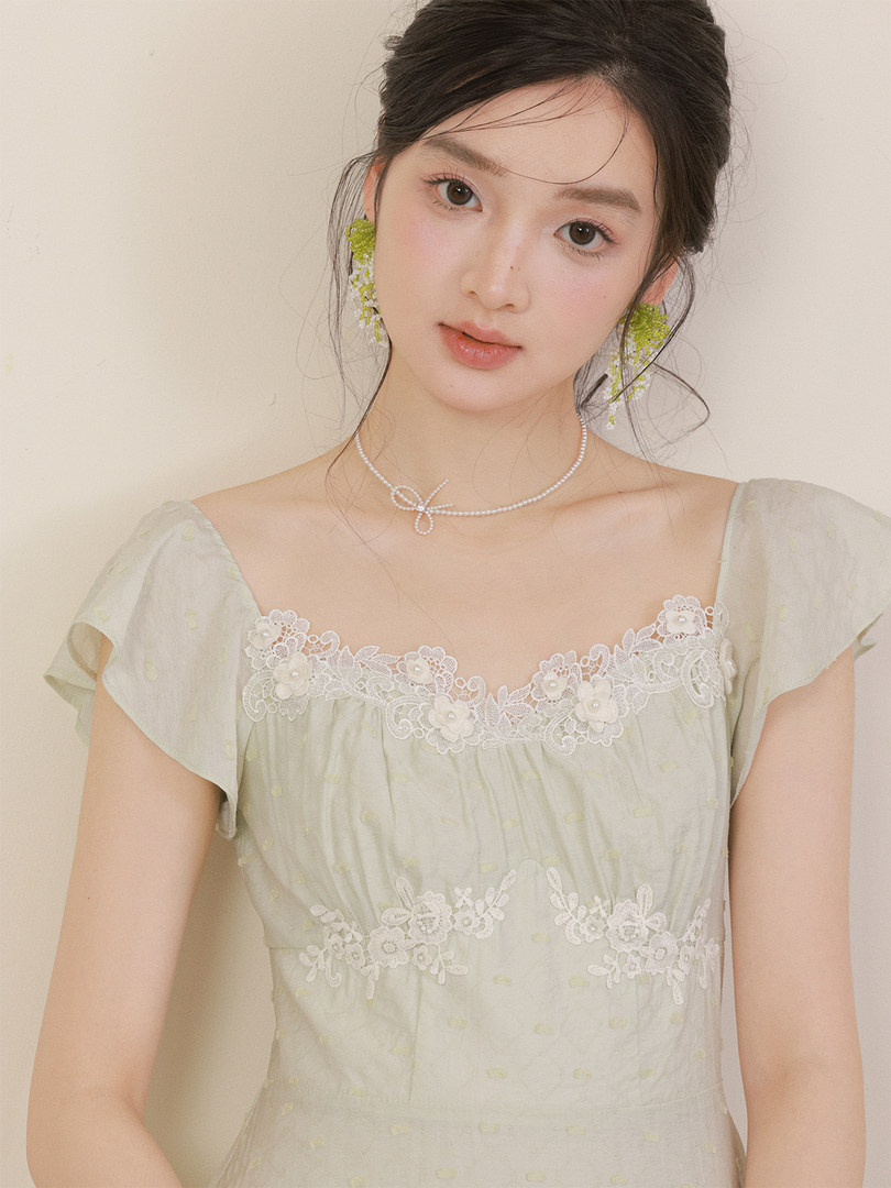 Model wearing a light pastel lace dress with floral trim