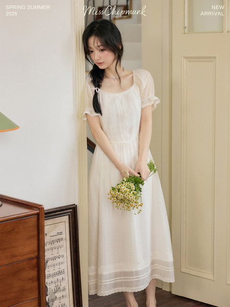 Woman wearing a white puff-sleeve dress in a styled indoor setting