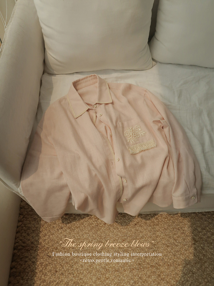Light pink embroidered button-up blouse displayed on a sofa