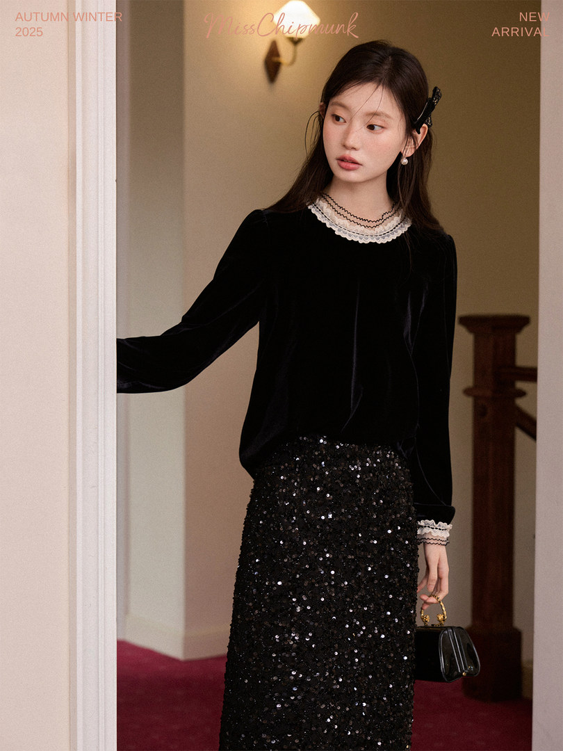 Model wearing a black velvet top with a sequined skirt and a small handbag