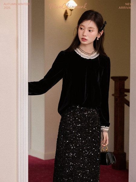 Model wearing a black velvet top with a sequined skirt and a small handbag