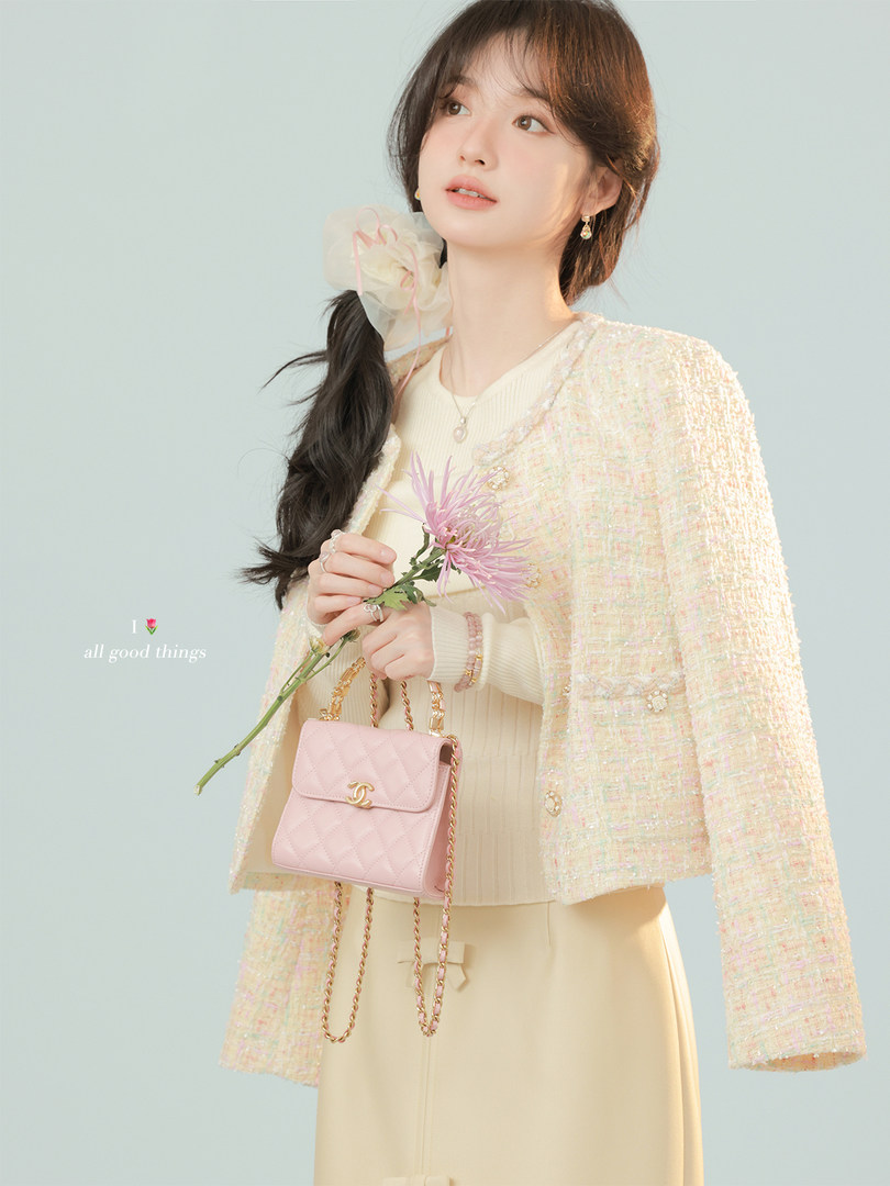 Model wearing a pastel tweed jacket with a pink chain-strap handbag