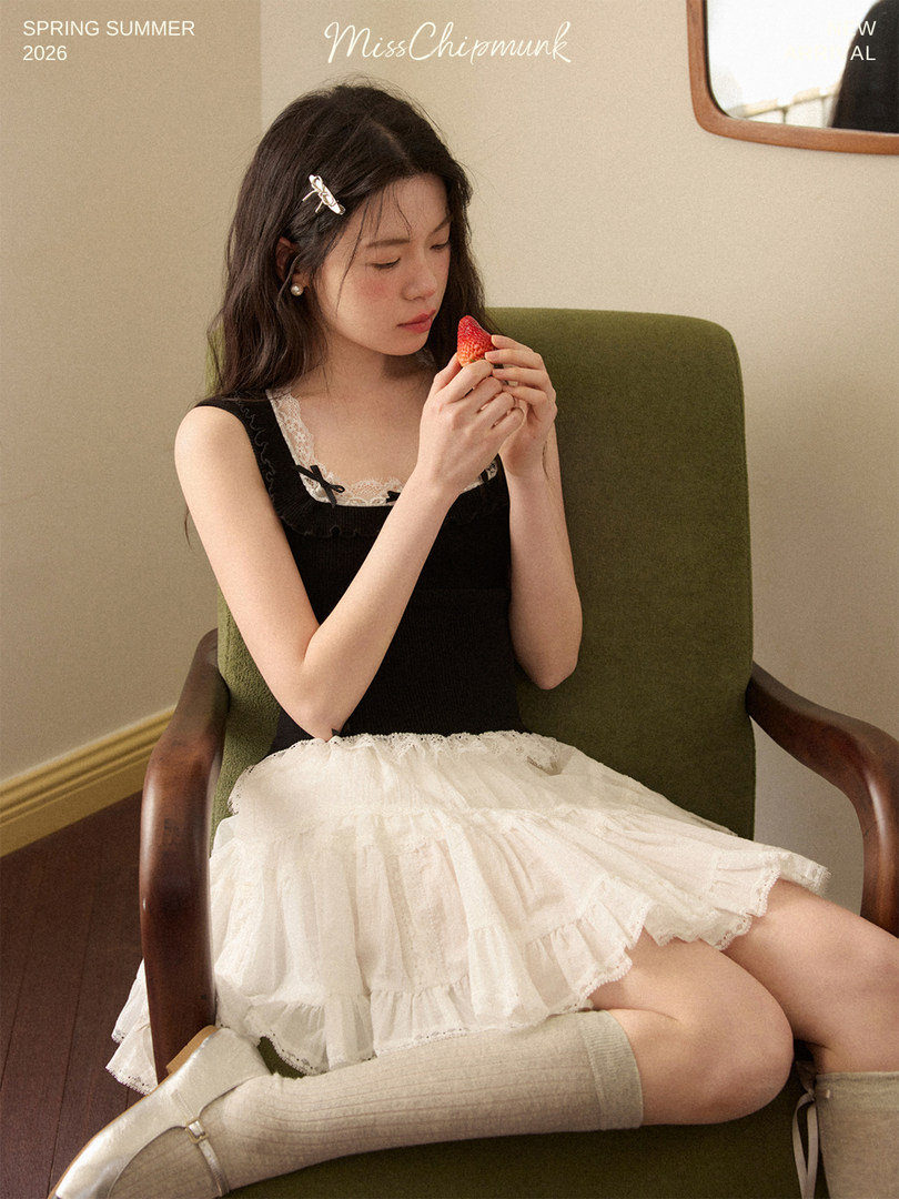 Young woman wearing a black lace-trim top with a white layered skirt in a styled fashion photo