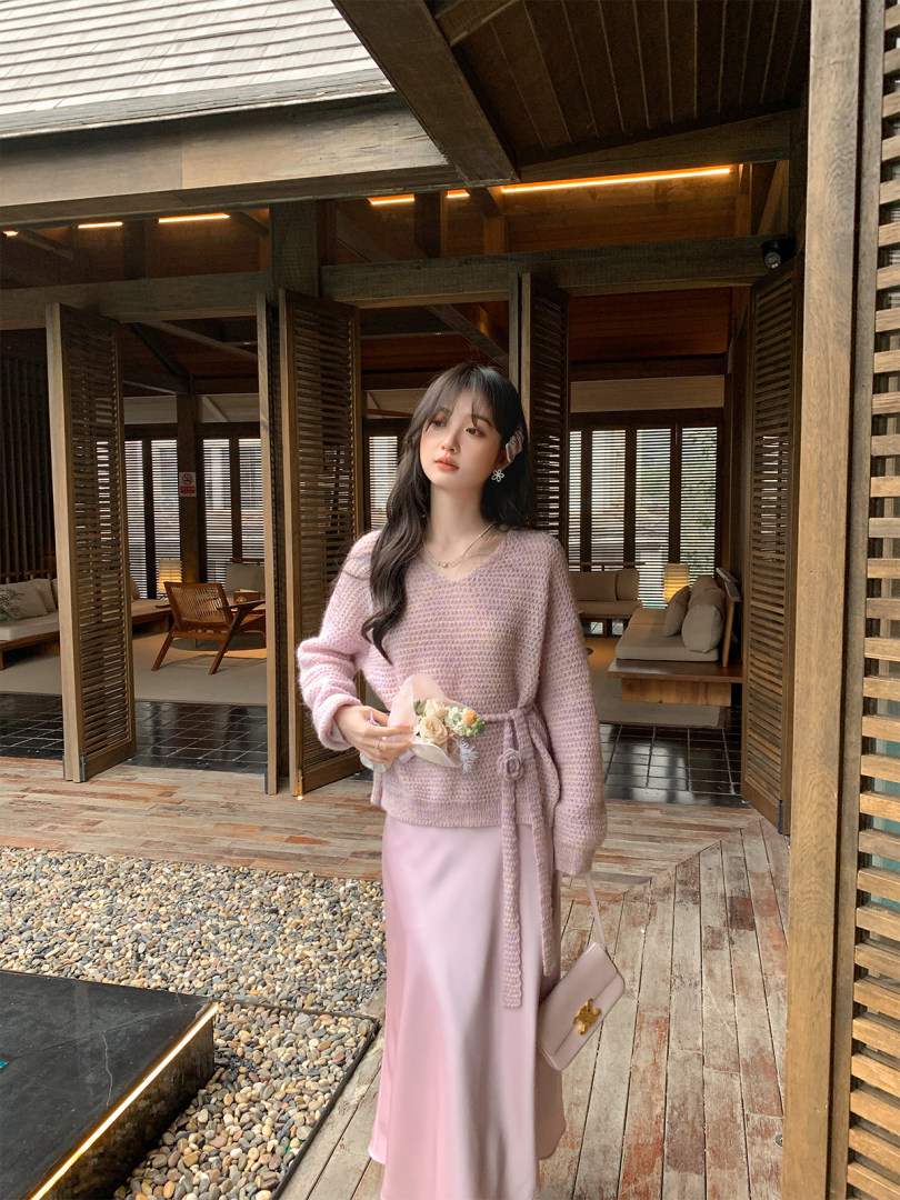 Woman wearing a pink knitted sweater with a matching skirt and handbag