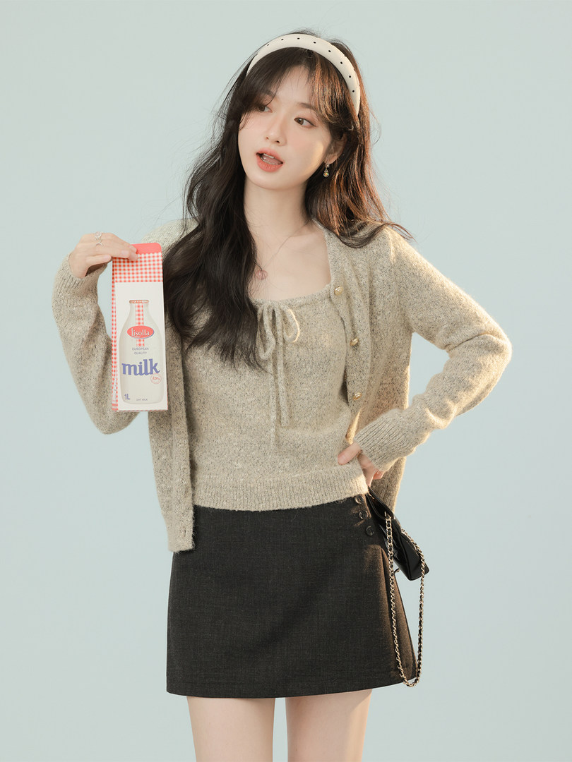 Woman modeling a beige cardigan sweater with a black mini skirt