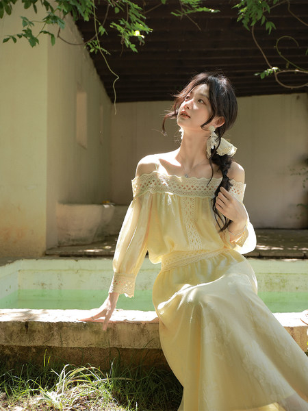 Model wearing a pale yellow off-shoulder lace dress outdoors