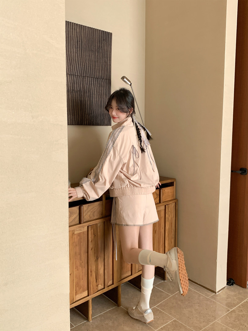 Model wearing a light beige sporty jacket and matching shorts set