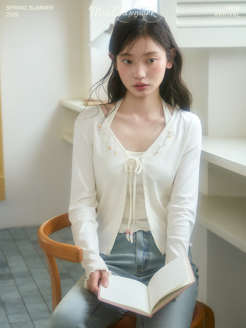Model wearing a white tie-front cardigan and top with jeans