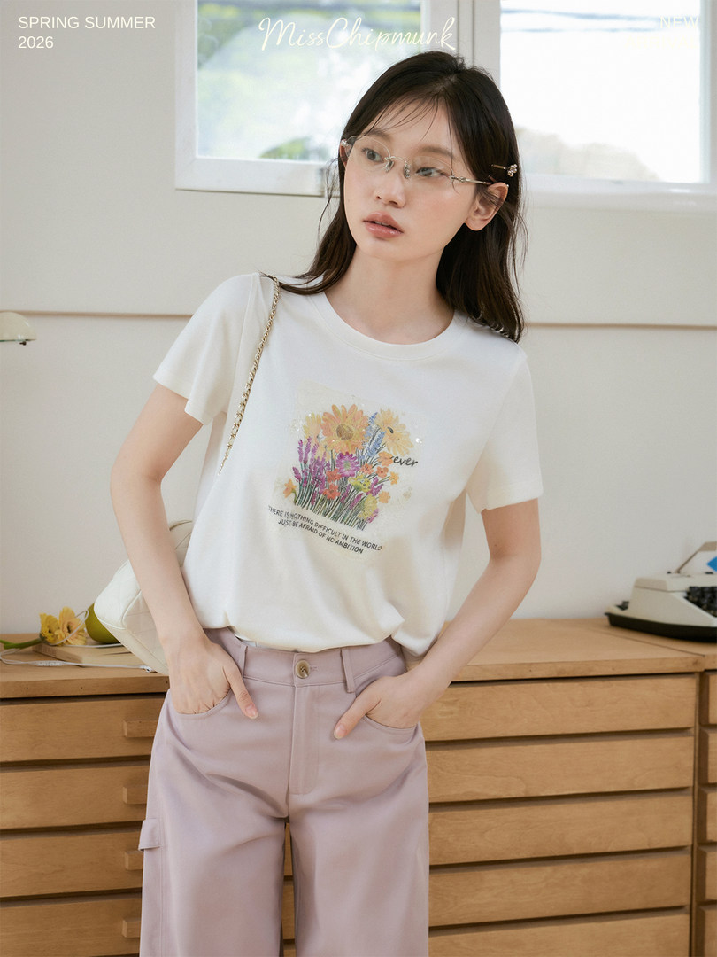 Model wearing a white floral graphic T-shirt with light pink pants