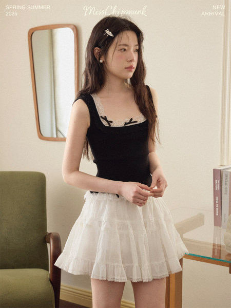 Model wearing a black lace-trim camisole top with a white tiered skirt
