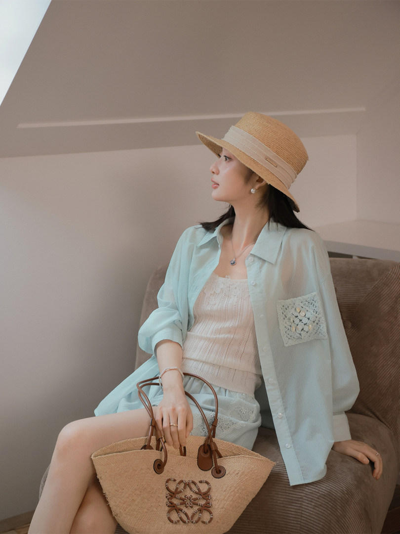 Woman wearing a light summer outfit with a straw hat and woven tote bag
