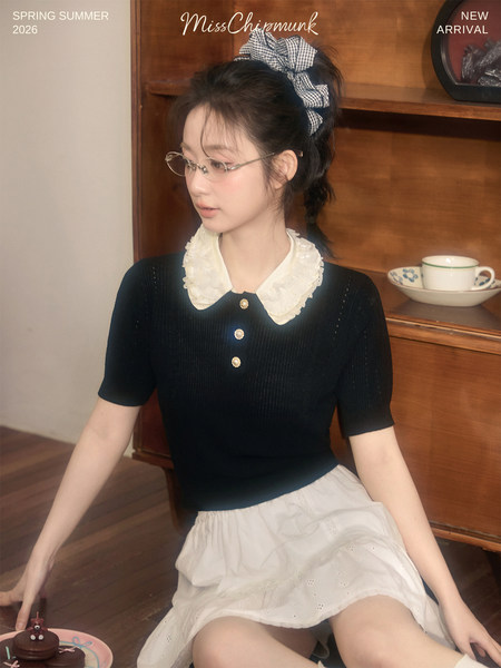 Model wearing a black short-sleeve top with a white lace collar and a cream skirt