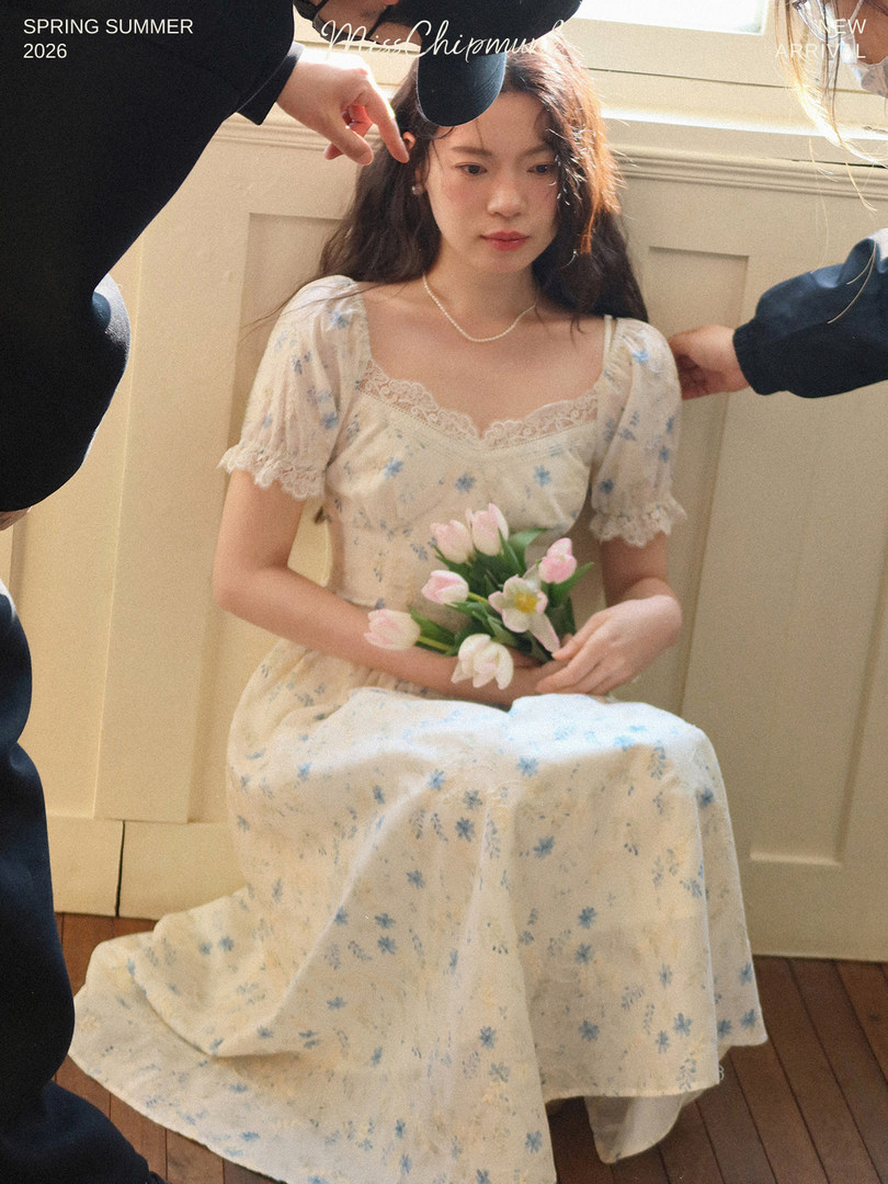 Woman wearing a light floral dress with lace trim and puff sleeves