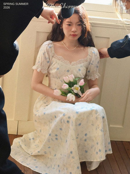 Woman wearing a light floral dress with lace trim and puff sleeves