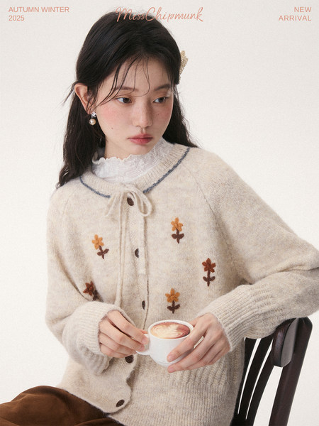 Model wearing a cream knitted floral cardigan with buttons and a bow tie detail