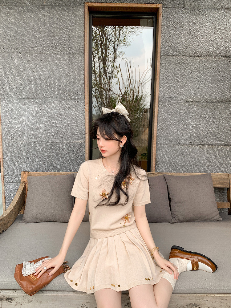 Woman wearing a beige short-sleeve dress with floral embellishments